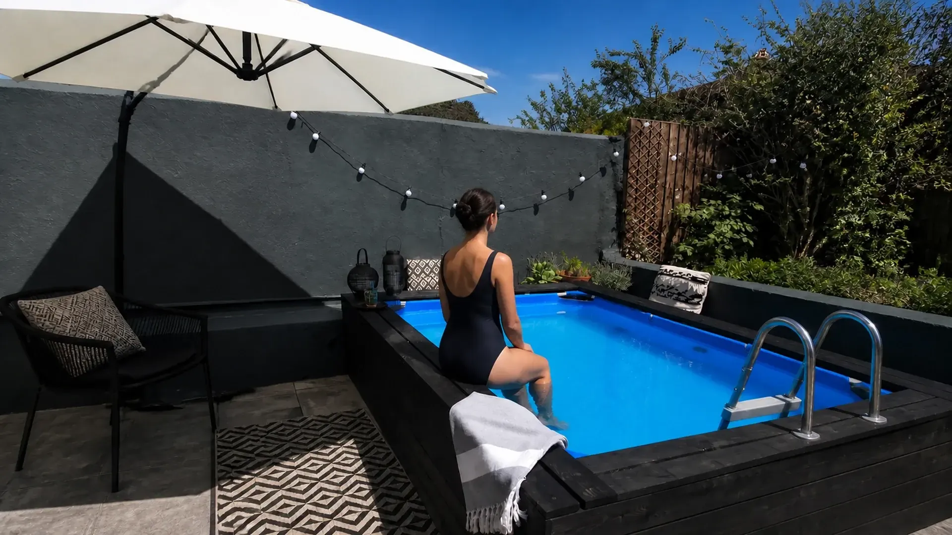 Mujer disfrutando una piscina de fibra instalada en un patio residencial