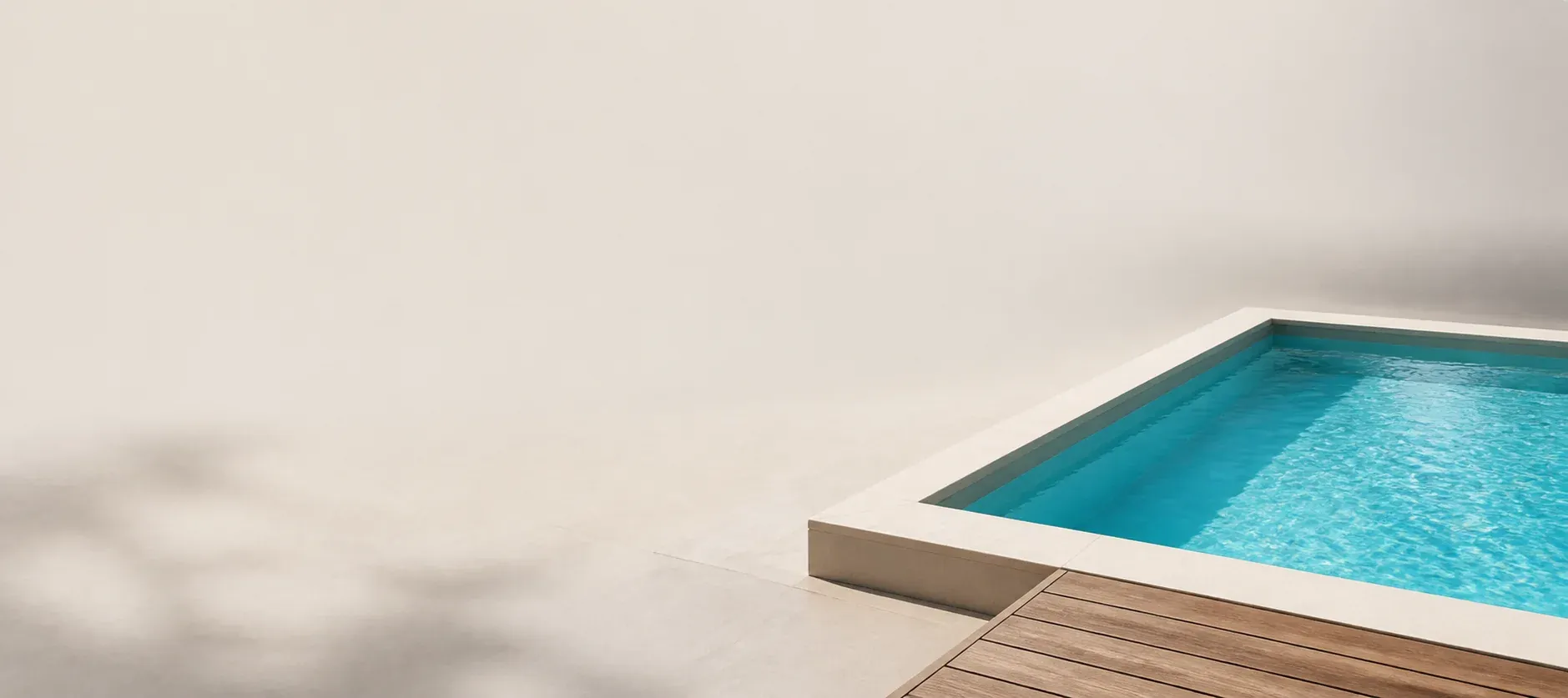 Piscina rectangular de agua turquesa con borde de piedra y terraza de madera
