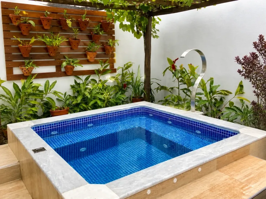 Spa con mosaicos azules integrado a un patio con vegetación